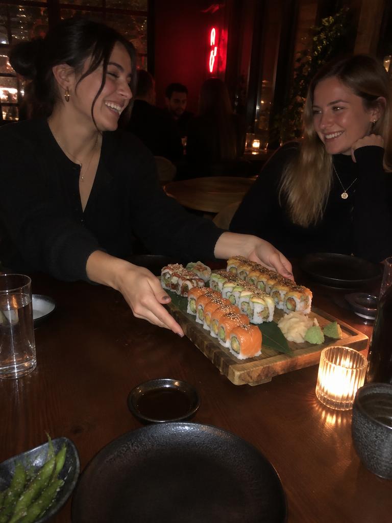 Two friends sharing sushi at a restaurant at night